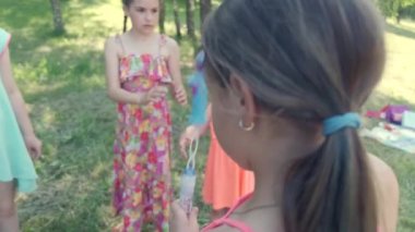 Güzel bir kız baloncukları üflüyor ve arkadaşları onların peşinden koşuyor. Mutlu çocuk.