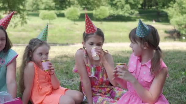 Las chicas con vestidos elegantes celebran su cumpleaños y beben refrescos. Niños felices. — Vídeos de Stock