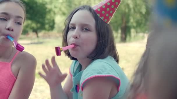 Щаслива група дітей, які святкують день народження в саду зі свистком . — стокове відео