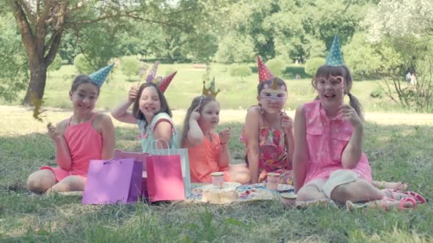 Los niños con máscaras de carnaval celebran su cumpleaños. Miran en el marco. — Vídeo de stock