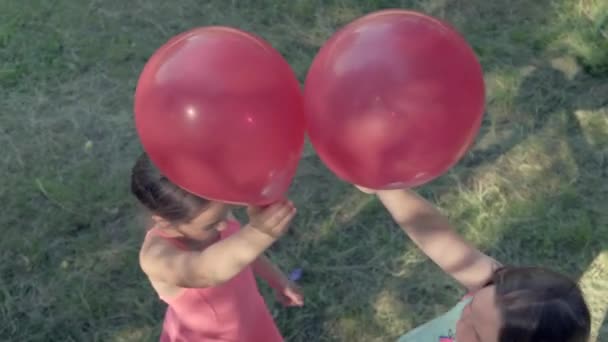 Twee mooie meisjes spelen met ballonnen. Spelen in de natuur. — Stockvideo