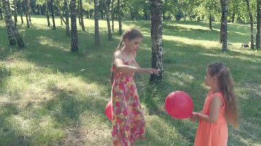 Elbiseli iki kız balonlarla oynuyorlar. Kız balonu patlattı..