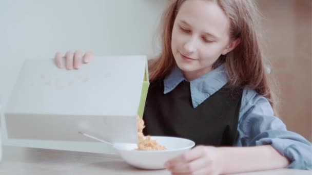 Ein schönes Mädchen frühstückt mit Cornflakes. Müsli in einen Teller gießen. — Stockvideo