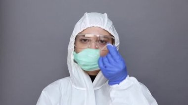 Koruyucu kostümlü kadın tıbbi maske takıyor.