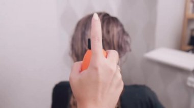 Bir kadının eli ıslak saçlara koruyucu sprey sıkar. Profesyonel saç bakımı..