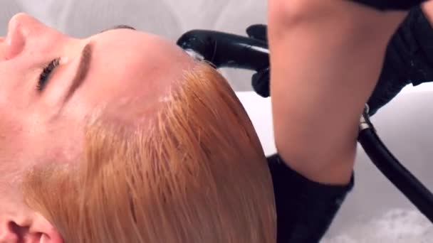 Le coiffeur rince la teinture après coloration des cheveux. Salon de beauté. — Video