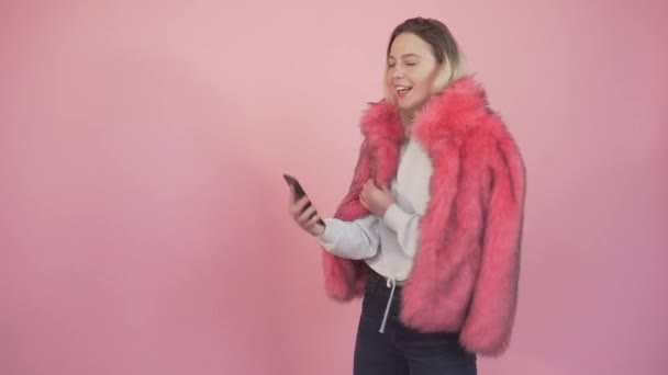 Krásná mladá dívka drží telefon v ruce a vezme selfie. — Stock video