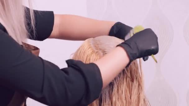 Uma menina em um salão de beleza tinge as raízes de seu cabelo branco. — Vídeo de Stock