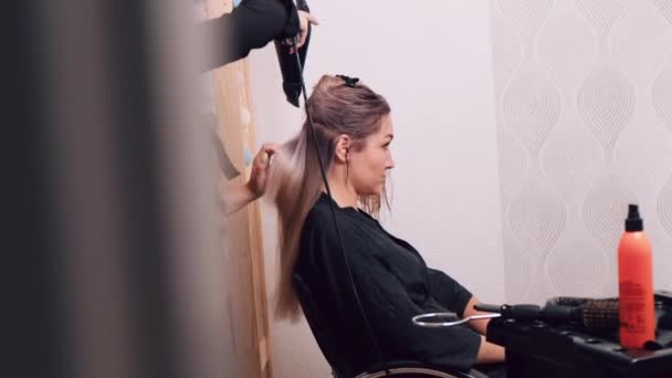 Młoda kobieta wysuszyć włosy z suszarką do włosów w salonie piękności, zrobić jej włosy. — Wideo stockowe