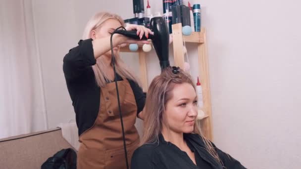 Ung vacker kvinna torka håret i en skönhetssalong. — Stockvideo