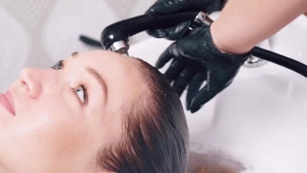 美容師はお客様の髪に水で染料を洗い流します。美容室. — ストック動画