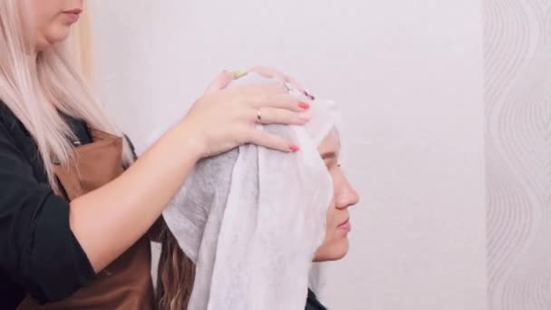 Cabeleireiro em um salão de beleza limpa o cabelo molhado com uma toalha. Cabelo loiro. — Vídeo de Stock