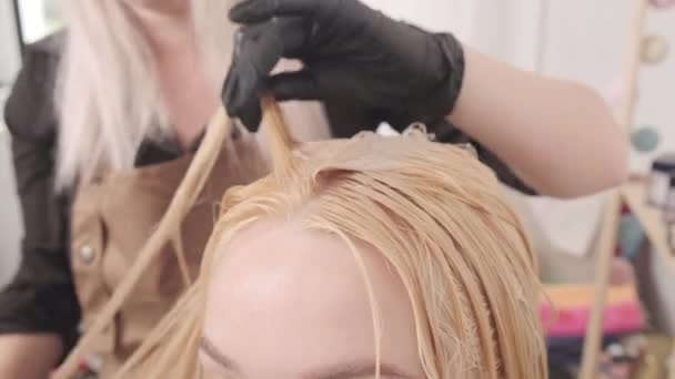Hermosa joven en un salón de belleza se tiñe el pelo. Cuidado del cabello. — Vídeos de Stock