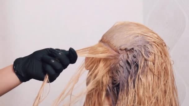 一个在美容院里的女孩用刷子把头发的根涂成了白色. — 图库视频影像