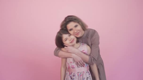 Bela jovem mãe abraça sua menina, olha para a câmera. — Vídeo de Stock