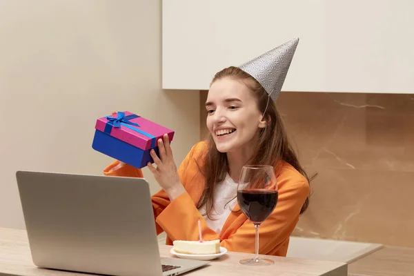 La joven felicita por la fiesta. Hay un portátil en la mesa. —  Fotos de Stock