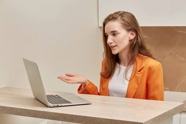 Una hermosa joven se comunica a través de enlace de vídeo con sus colegas. — Foto de Stock