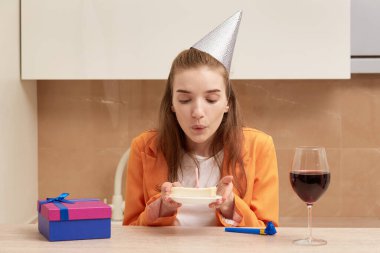 Güzel genç bayan doğum günü pastasındaki mumları üflüyor..