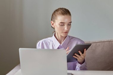 Genç bir kadın elinde tabletle internette çalışıyor..