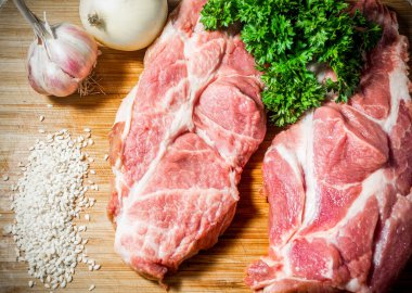 İki taze domuz pirzolası tahtanın üzerinde susam tohumunun yanında maydanoz chasnok soğan yakın plan et yemeği konsepti