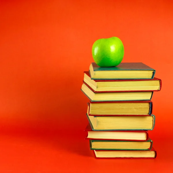 Bir yığın kitap ve yeşil elma. Bilgi ve öğrenimin, eğitimin ve gelişimin sembolü. Metin için boşluk