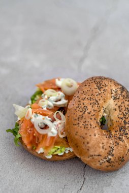 Krem peynirli somon simidi, mermer tezgahta taze otlar ve sebzeler.