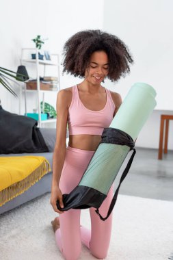 Evde yoga minderini açan afro kadın.