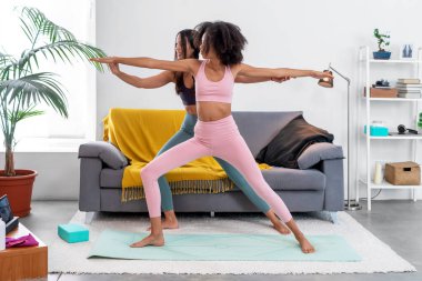 Yoga öğretmeni, Savaşçı II pozunu düzeltiyor.