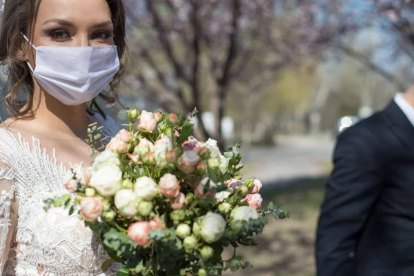 bride and groom in protective masks. Wedding during the period of quarantine and pandemic Covid 19-20, coronavirus wedding. The groom and the bride in wedding dresses, with dresses in protective masks. Coronavirus pandemic, quarantine events wedding,