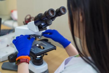 Mikroskop ile seçici odak laboratuvar asistanı mikroskopla incelerken notlar alan bir bilim adamı mikroskoba bakıyor. Yakın plan doktor laboratuvar asistanı mikroskopla bir hastaya kan testi yapıyor.