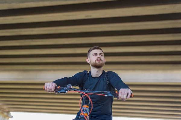 自転車に乗ってオープンロードで夕日に自転車に乗るひげを生やしたサイクリストの選手男のクローズアップ肖像画 屋外だ 春のスポーツ その男は２５歳です サイクリング春の自転車に乗る 極端なサイクリング アクティブなライフスタイル — ストック写真