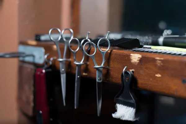 Hairdressing scissors in wooden stand hairdresser\'s workplace. A set of scissors, combs, nozzles for cutting hair of a machine, on a wooden table in a barbershop.