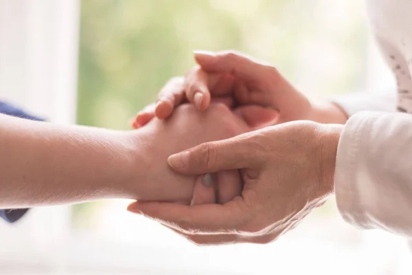 Yaşlı bir kadının yaşlı ellerini tutan genç bir el genç bir kızın ellerine dokunuyor, yakından. Psikolojik yardım, doktor bir terapist, bir psikolog hastanın elini tutuyor. Umut ver, yaşlı ve genç eller, yardım et, yardım et