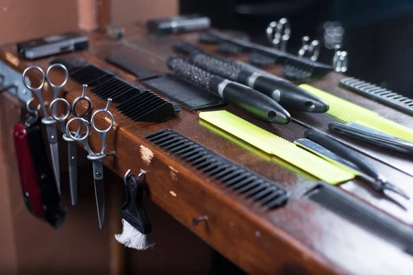 Hairdressing scissors in wooden stand hairdresser\'s workplace. A set of scissors, combs, nozzles for cutting hair of a machine, on a wooden table in a barbershop.
