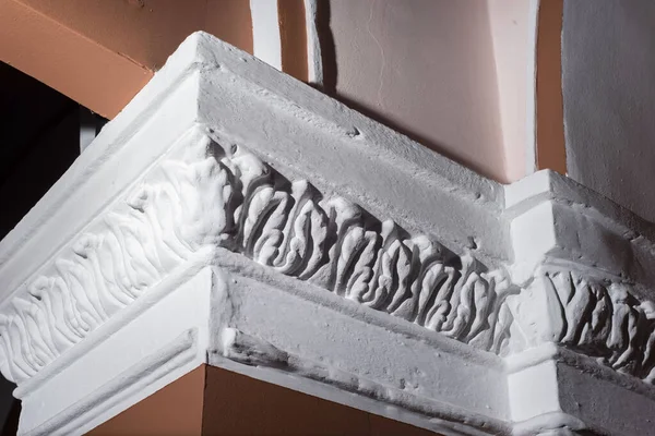 detail of intricate corner crown molding.intricate angle casting detail. Handmade finish of the white corner of the wall inside the house on a beige wall. architectural design interior