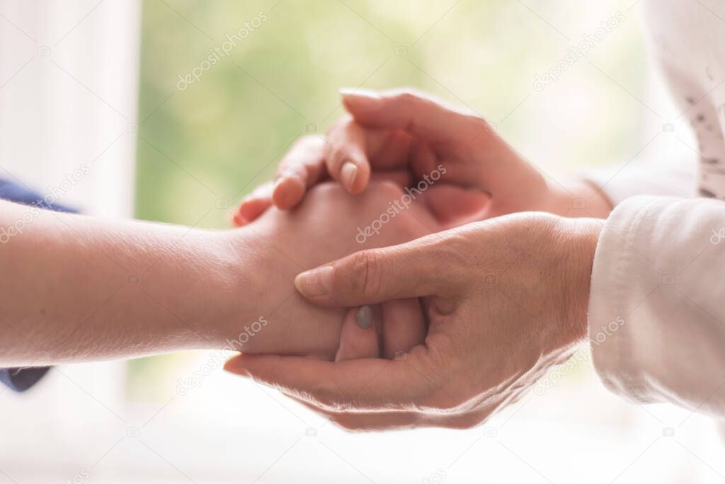 A young hand holding an elderly pair of hands hands of an old woman touch the hands of a young girl, closeup. Psychological assistance, the doctor is a therapist, a psychologist takes the patient's hand. Give hope, hands old and young, helping, helpi