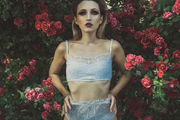 一个28岁的小女孩，穿着内衣裤，背景是一朵红玫瑰的质地。在温暖的皮肤的创意艺术色调。天然花卉背景，内衣广告 — 图库照片