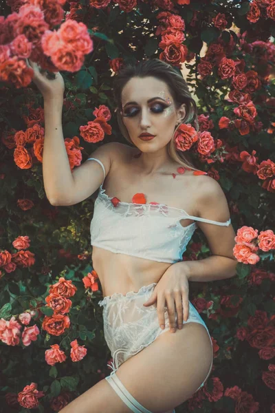 一个28岁的小女孩，穿着内衣裤，背景是一朵红玫瑰的质地。在温暖的皮肤的创意艺术色调。天然花卉背景，内衣广告 — 图库照片