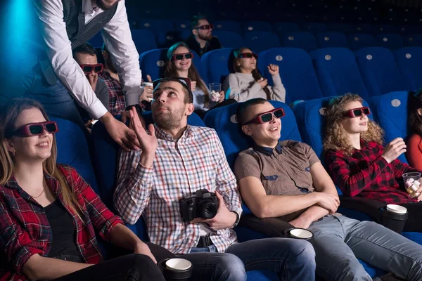 映画館の警備員は 映画を見せながら 違法なビデオの後ろに若い男を捕まえた 映画の中で海賊を撃つ 映画館で映画を観たり椅子に座ったりポプコを食べたりしながら座っています — ストック写真