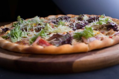 İnce dilimlenmiş pepperoni, Amerikan usulü pizzacılarda popüler bir pizza çeşididir. Bir tepside yakın plan pizza, sebze ve etle birlikte, kırsal bir tarzda. Olağandışı bir açı. Salata, sebzeli pizza, et yemeği. Dost canlısı pizza. Pizzanın dokusu. Yiyecekler. Ba