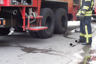 İtfaiye bir konut binasındaki ateşleme kaynağında çalışıyor. Üniformalı insanlar yangın hortumunu açıp yangını söndürmek için hazırlayacaklar. Gösteriş