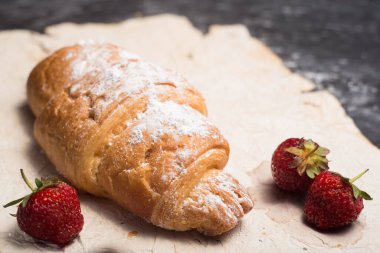 Çilekli, kirazlı kruvasan. Köy tarzında, karanlık soyut bir arkaplanda..