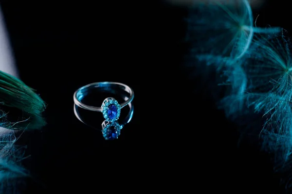 a beautiful ring in white gold with a sapphire stone. On a mirror background. Creative decoration