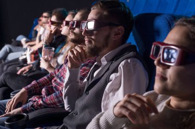 Farklı cinsten bir grup genç, sinemada sandalyede oturup film izliyor, patlamış mısır yiyorlar. Üç boyutlu gözlüklerle. Filmin özel gösterimi. Farklı nesillerden genç insanlar, binyıllar, Z jenerasyonu, Y jenerasyonu dahil. Kızlar ve bo