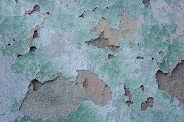 yeşil çatlamış alçı dokusu, ovulmuş gri boya elementleri. Dokulu bir sokak duvarının pastel tonu. Duvarda çatlak, eski yeşil alçıda birden fazla delik var. Yeşil alçılı tuğla duvar dokusu. Gri boyalı retro duvar yapısı. G