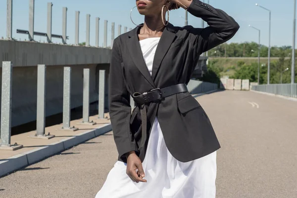 black girl in a business suit on top of a white dress. Fashionable shot of an African girl on a background of blue sky. street style fashion. young african business girl in a business suit, fashion posing for an advertising magazine about business fa