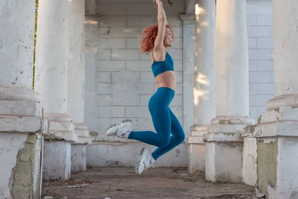 Young Red Haired Sportswoman Jumping Air Turquoise Tracksuit Leggings Background — Stock Photo, Image