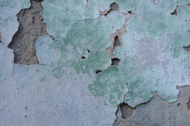 yeşil çatlamış alçı dokusu, ovulmuş gri boya elementleri. Dokulu bir sokak duvarının pastel tonu. Duvarda çatlak, eski yeşil alçıda birden fazla delik var. Yeşil alçılı tuğla duvar dokusu. Gri boyalı retro duvar yapısı. G