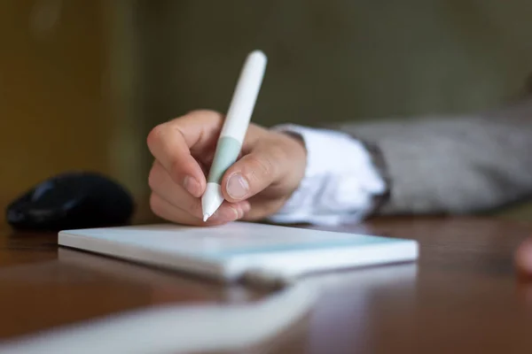 businessman sitting at the table, signs in a graphics tablet with a stylus. Closeup. Business. Electronic signature using a pen tablet Graphic designer using digital tablet and computer in the office