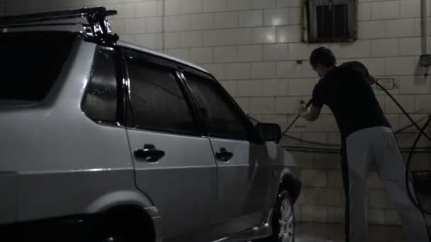 De man wast de zeep van de auto met een straal water onder druk van een kruimeldief — Stockvideo